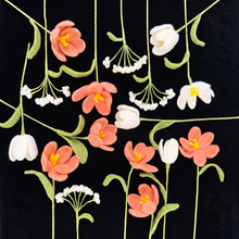 Assorted pink and white handmade crochet flowers with green stems displayed on a black background